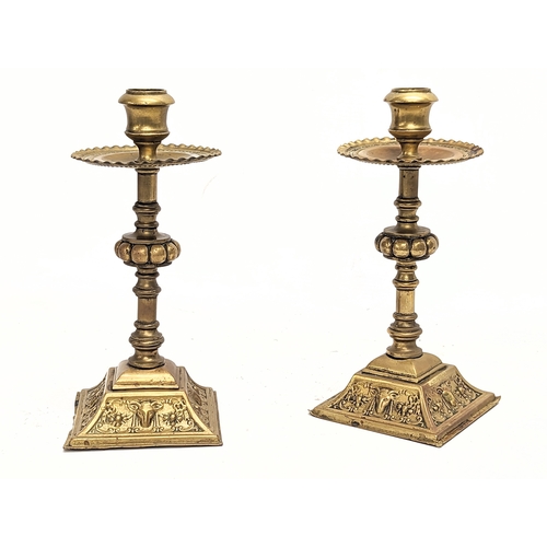 30E - A pair of 19th century ornate brass candlesticks with ram head decoration. 23cm