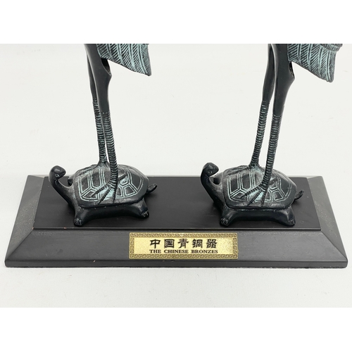 235 - A pair of Chinese bronze cranes on stand. 21x8x27cm