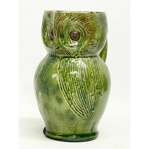 47 - A late 19th century Farnham Pottery green glazed earthenware owl jug. 12x14cm.