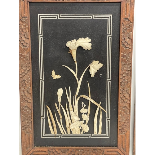 323 - A pair of early 20th century Japanese lacquered panels with carved bone motif in wooden frames. Circ... 