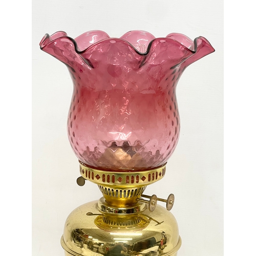 595 - A vintage brass double burner oil lamp with Ruby Glass shade. 42.5cm