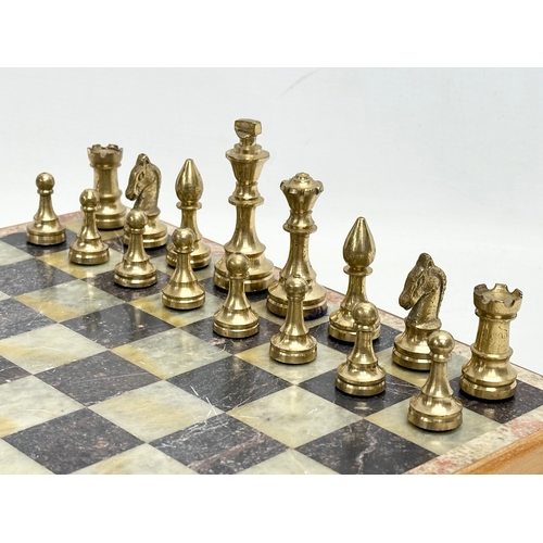 211D - An onyx and brass chess set. 30.5x30cm