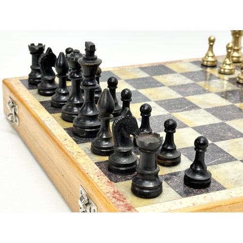 211D - An onyx and brass chess set. 30.5x30cm