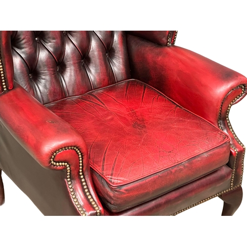 1006 - An ox-blood deep button leather wingback armchair. (5)