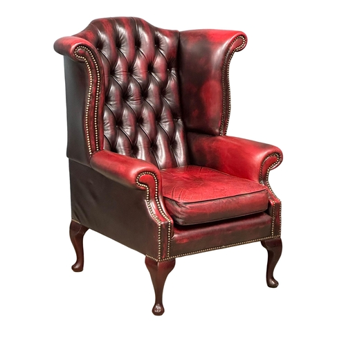 1006 - An ox-blood deep button leather wingback armchair. (5)