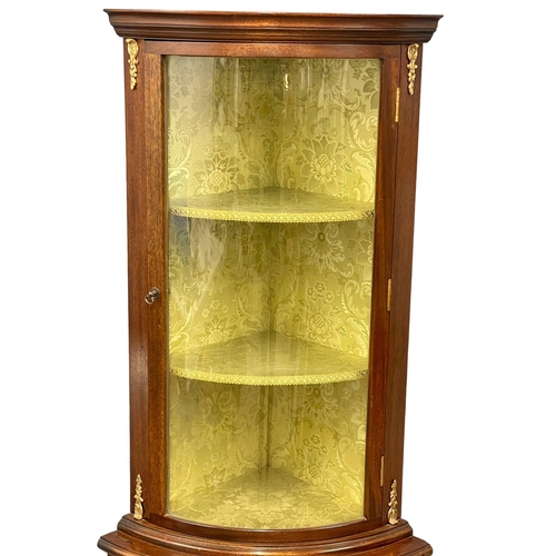 1016 - A mahogany bow front corner cabinet with brass ormolu mounts. 55x37x169.5cm (3)