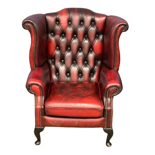 839 - A pair of ox-blood deep button leather wingback armchairs. (7)