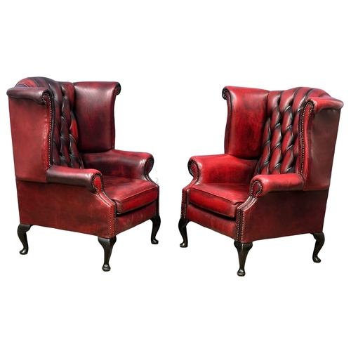 839 - A pair of ox-blood deep button leather wingback armchairs. (7)