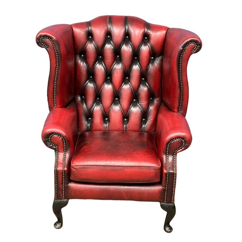 839 - A pair of ox-blood deep button leather wingback armchairs. (7)