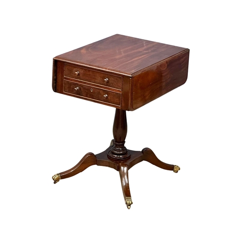 927 - A Regency mahogany double sided pedestal drop leaf table on brass lion paw feet. Circa 1810. 82x61x7... 