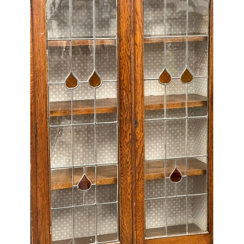 948 - A large early 20th century oak bookcase with stained glass doors and fitted shelves. Circa 1920-1930... 