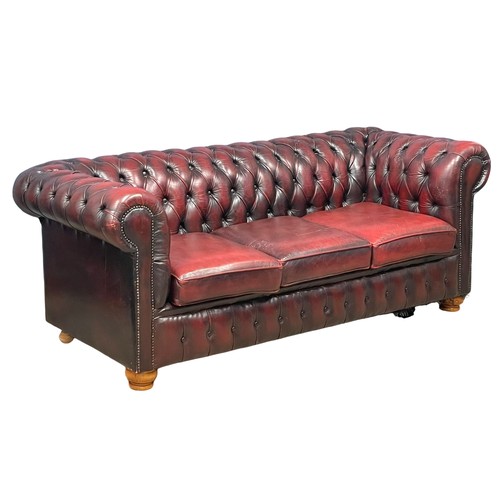 1202 - An ox-blood deep button leather 3 seater sofa. 197cm. (10)