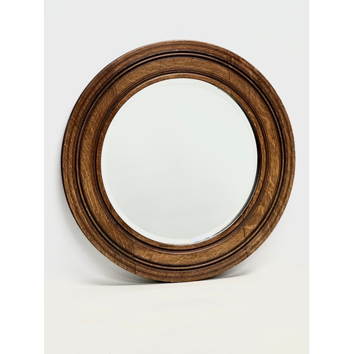 71 - An Edwardian oak spinning wheel bevelled mirror. 50.5cm