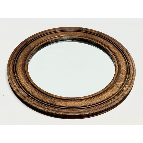 71 - An Edwardian oak spinning wheel bevelled mirror. 50.5cm