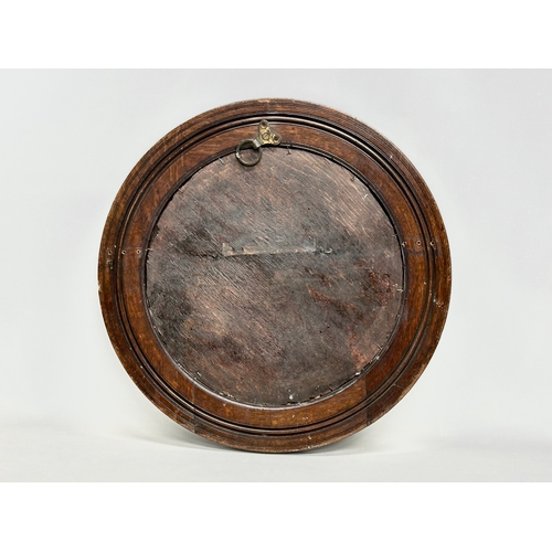 71 - An Edwardian oak spinning wheel bevelled mirror. 50.5cm