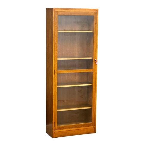 952 - A large vintage oak glazed door cabinet with adjustable shelves. 69x32x84cm