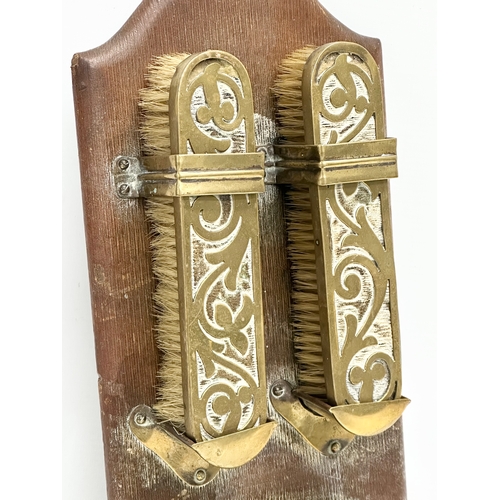 376 - An Art Nouveau brass wall hanging clothes brush set on leather bound panel. Circa 1900. 17x35cm