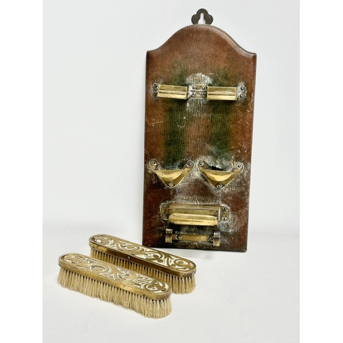 376 - An Art Nouveau brass wall hanging clothes brush set on leather bound panel. Circa 1900. 17x35cm