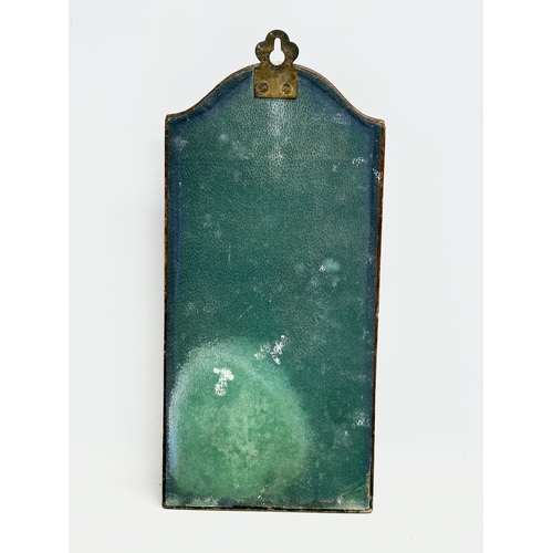 376 - An Art Nouveau brass wall hanging clothes brush set on leather bound panel. Circa 1900. 17x35cm