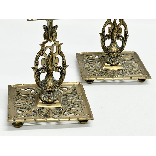 60G - A pair of Victorian pierced brass candlesticks with lion mask design and butterfly motif. 12x12x21cm