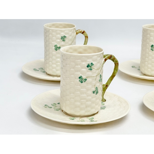 29 - An 8 piece Belleek ‘Shamrock’ coffee service. 1 green stamp mug and 7 brown stamps. Saucers measure ... 