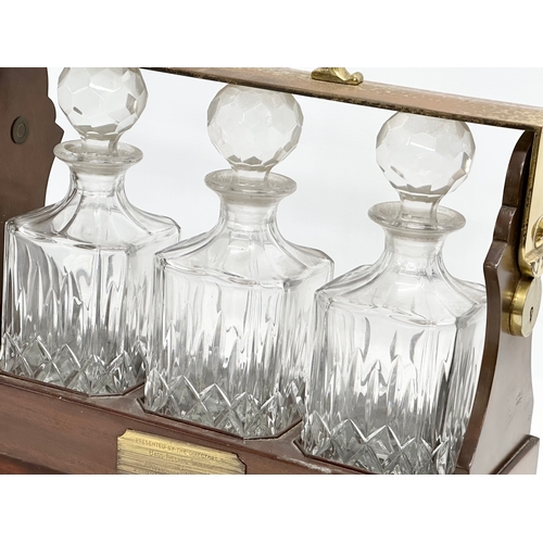 90 - A mahogany and brass tantalus with 3 matching crystal decanters. No key. 39x15x35cm