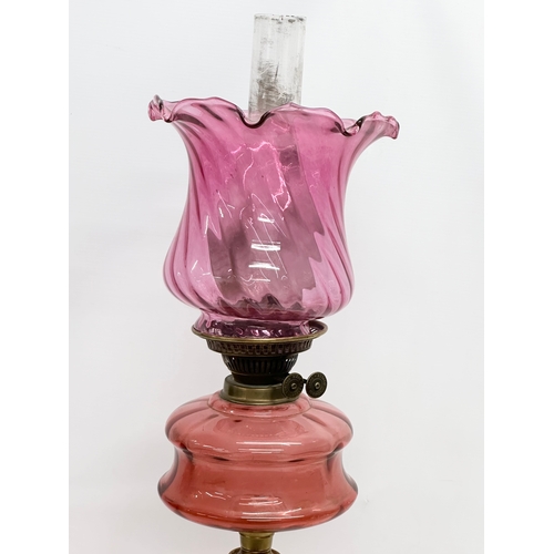 103 - A large Victorian oil lamp with Cranberry Glass bowl, brass column and later shade. 89cm