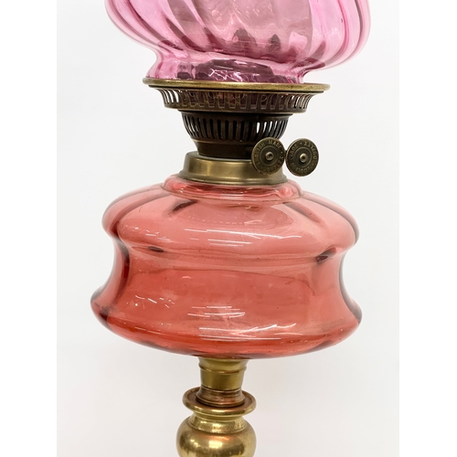 103 - A large Victorian oil lamp with Cranberry Glass bowl, brass column and later shade. 89cm