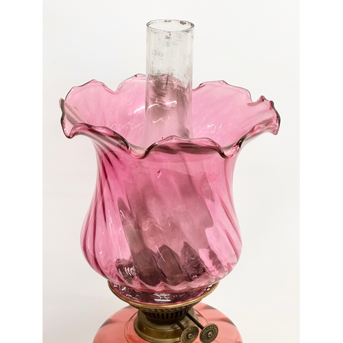 103 - A large Victorian oil lamp with Cranberry Glass bowl, brass column and later shade. 89cm