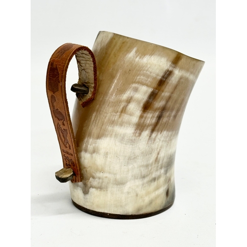 666 - A horn drinking cup with leather handle and wooden base. 13x8x13cm