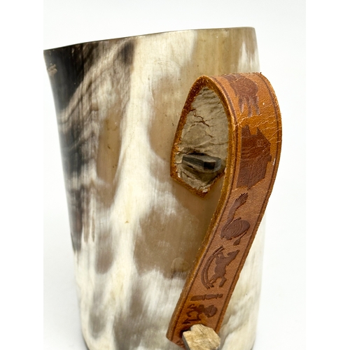 666 - A horn drinking cup with leather handle and wooden base. 13x8x13cm