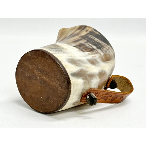 666 - A horn drinking cup with leather handle and wooden base. 13x8x13cm