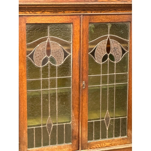 925 - An early 20th century Art Nouveau oak bookcase on stand with stained glass panel doors. Circa 1910-1... 