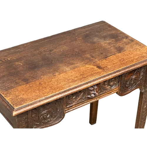 931 - A Victorian oak side table with carved wild flower motif and Man of the Forest drawer. Circa 1870. R... 