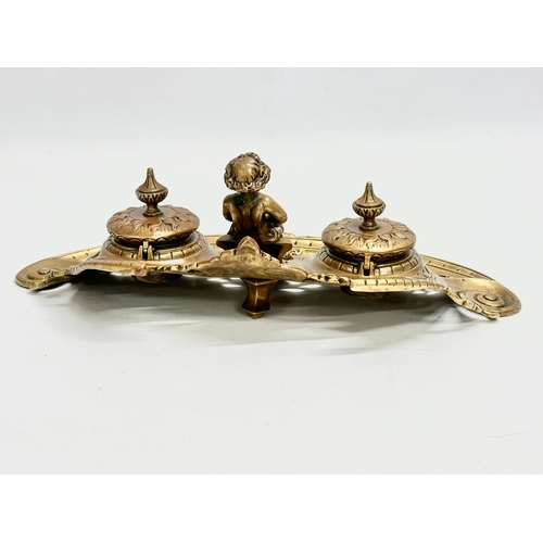 37 - A Late 19th Century brass inkstand/inkwell with sitting putti and pierced brass base. 32x20x11cm