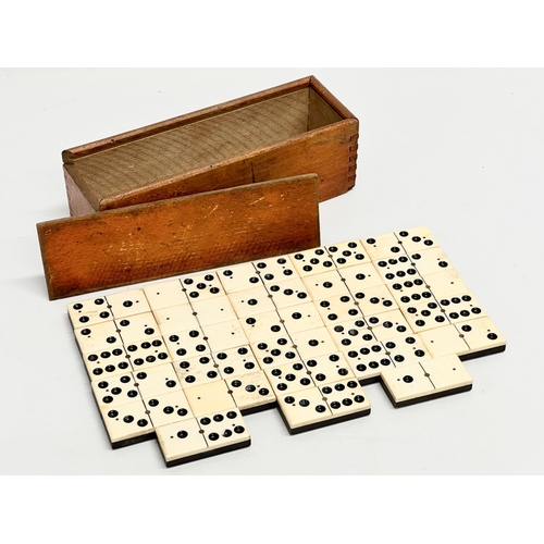 40 - A collection of 19th Century bone and ebony dominoes with wooden box. Pieces 5.5cm. Box 21cm.