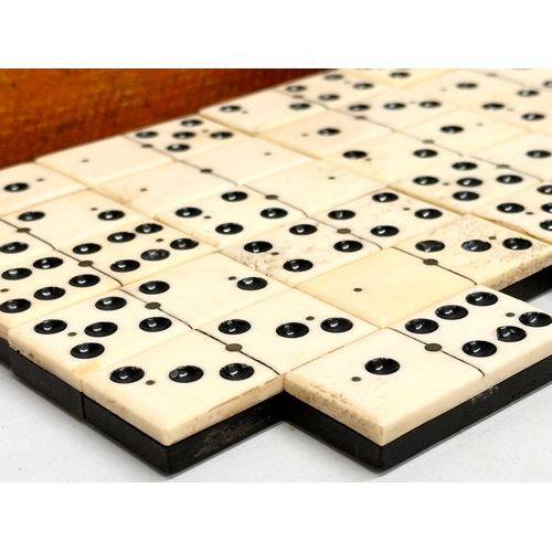 40 - A collection of 19th Century bone and ebony dominoes with wooden box. Pieces 5.5cm. Box 21cm.