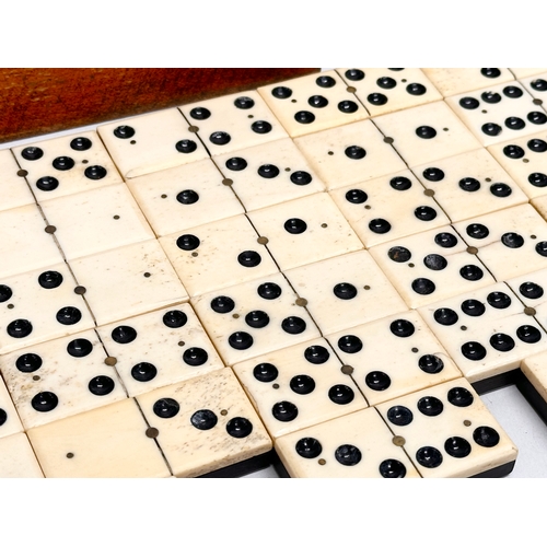 40 - A collection of 19th Century bone and ebony dominoes with wooden box. Pieces 5.5cm. Box 21cm.