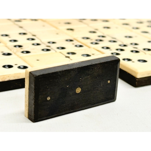 40 - A collection of 19th Century bone and ebony dominoes with wooden box. Pieces 5.5cm. Box 21cm.