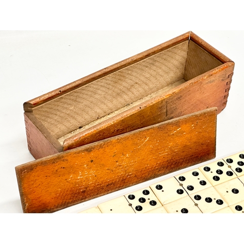 40 - A collection of 19th Century bone and ebony dominoes with wooden box. Pieces 5.5cm. Box 21cm.