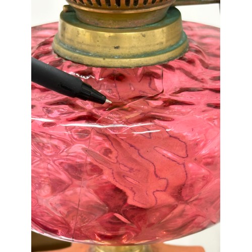 320 - A large Victorian Ruby glass oil lamp with brass Corinthian style column. 60cm