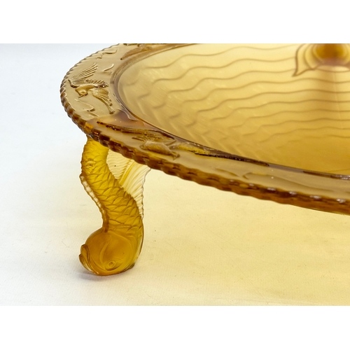 124 - A large 1930’s S. Reich & Co amber glass centrepiece bowl with sea fish design rim and raised on 3 k... 