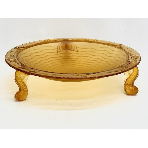 124 - A large 1930’s S. Reich & Co amber glass centrepiece bowl with sea fish design rim and raised on 3 k... 