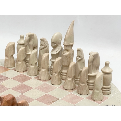 284 - An African soapstone chess set. 40.5cm