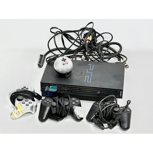 570 - A PS2 (PlayStation 2) console with 3 controllers.