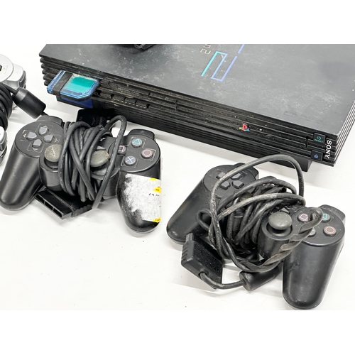 570 - A PS2 (PlayStation 2) console with 3 controllers.