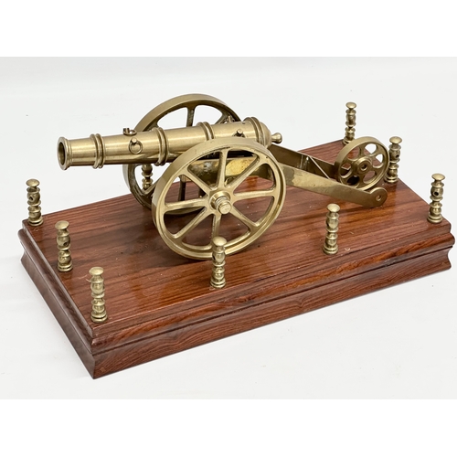 674 - 2 brass canons on stands. Wooden stand measures 31x16x16cm