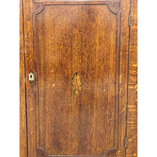 1063 - A George III inlaid oak wall hanging corner cabinet with fitted shelves. Circa 1790-1800. 69.5x38.5x... 