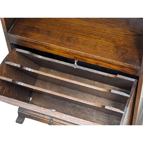 1106 - A vintage oak open bookcase with drop down paper rack. 48.5x22.5x105cm