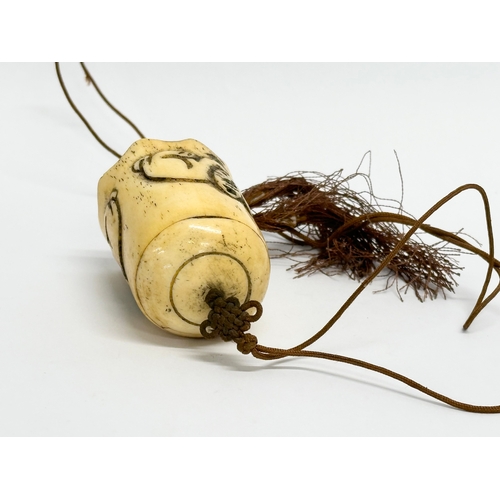 153 - A Late 19th/Early 20th Century Chinese carved bone bell. 49cm including string. Bone measures 6cm